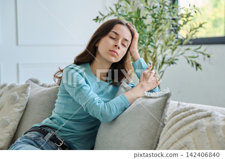 Exhausted young woman sitting on couch with closed eyes resting at home Exhausted young woman sitting on couch with closed eyes resting at home 142406840