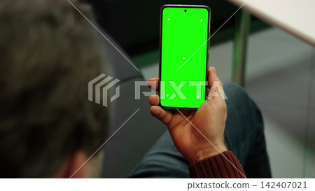 Man holding smartphone with green screen and tracking markers close up over shoulder view. Mobile phone mockup display chroma key space for application web template. Digital device usage Man holding smartphone with green screen and tracking markers close up over shoulder view. Mobile phone mockup display chroma key space for application web template. Digital device usage 142407021