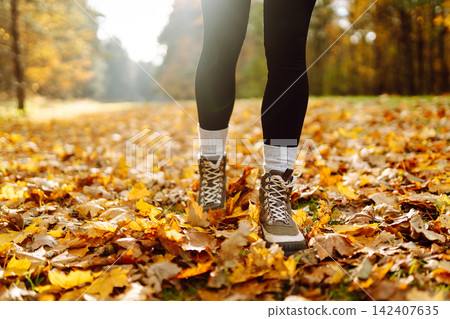 Female legs in boots walking through fallen trees in autumn park. Nature, travel concept. Female legs in boots walking through fallen trees in autumn park. Nature, travel concept. 142407635