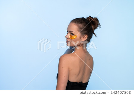 Young woman applying luxurious gold hydrogel patches under her eyes for skincare, promoting beauty and self-care Young woman applying luxurious gold hydrogel patches under her eyes for skincare, promoting beauty and self-care 142407808