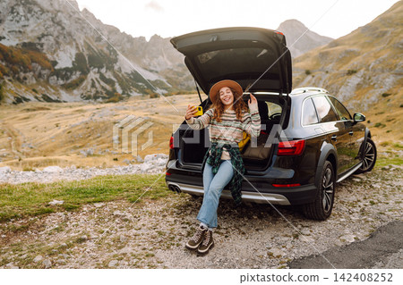 Young traveler woman taking a selfie by her car in the mountains during sunset. Lifestyle, travel Young traveler woman taking a selfie by her car in the mountains during sunset. Lifestyle, travel 142408252