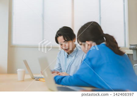 畫面中，男女員工在辦公桌前一起工作，一起審閱文件。 142408397
