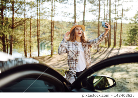 Woman in plaid shirt enjoys peaceful sunset by the lake. Journey by car. Lifestyle, travel concept Woman in plaid shirt enjoys peaceful sunset by the lake. Journey by car. Lifestyle, travel concept 142408623