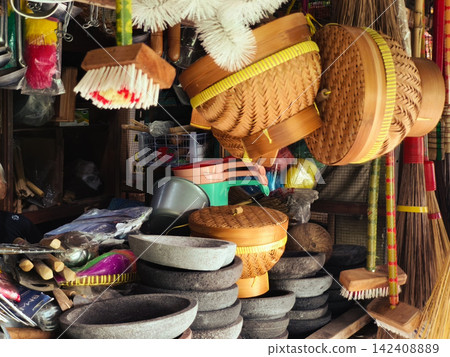 Traditional Indonesian handmade crafts and wooden kitchenware displayed for sale at Pasar Kotagede market in Yogyakarta, featuring woven bamboo goods, clay pottery, stone mortars, and household cleani Traditional Indonesian handmade crafts and wooden kitchenware displayed for sale at Pasar Kotagede market in Yogyakarta, featuring woven bamboo goods, clay pottery, stone mortars, and household cleani 142408889
