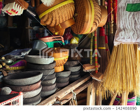 Traditional Indonesian handmade crafts and wooden kitchenware displayed for sale at Pasar Kotagede market in Yogyakarta, featuring woven bamboo goods, clay pottery, stone mortars, and household cleani Traditional Indonesian handmade crafts and wooden kitchenware displayed for sale at Pasar Kotagede market in Yogyakarta, featuring woven bamboo goods, clay pottery, stone mortars, and household cleani 142408890
