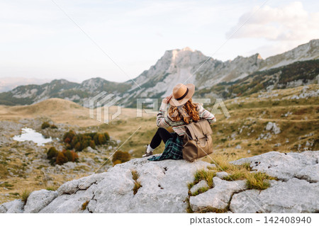 Happy woman stands on rocky terrain, gazing out at breathtaking landscape before her. Lifestyle. Happy woman stands on rocky terrain, gazing out at breathtaking landscape before her. Lifestyle. 142408940