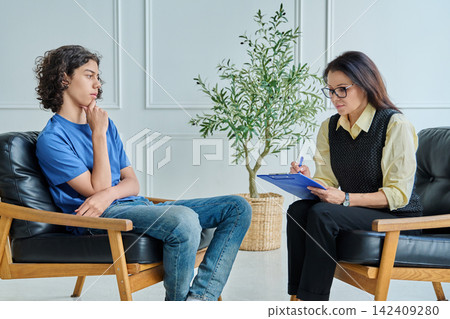 Smiling teenage student girl in glasses sitting on floor hugging knees. Smiling teenage student girl in glasses sitting on floor hugging knees. 142409280