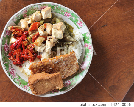 Top down overhead view of traditional Javanese food spread including rice, crispy fried egg, sambal, and side dishes served on a wooden table at Warung Kopi Klotok in Yogyakarta, Indonesia. Top down overhead view of traditional Javanese food spread including rice, crispy fried egg, sambal, and side dishes served on a wooden table at Warung Kopi Klotok in Yogyakarta, Indonesia. 142410006