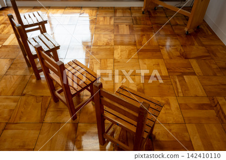A room with polished flooring and rows of wooden chairs. A room with polished flooring and rows of wooden chairs. 142410110