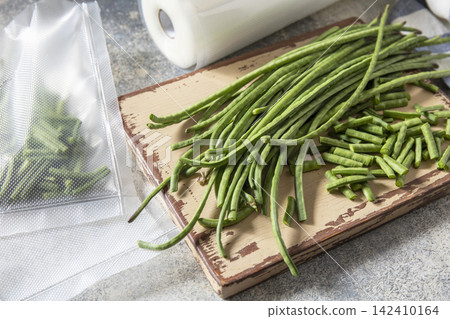 Vacuum sealed fresh green beans in packaging on a light grey background, healthy eating, zero waste, meal prep concept. Vacuum sealed fresh green beans in packaging on a light grey background, healthy eating, zero waste, meal prep concept. 142410164
