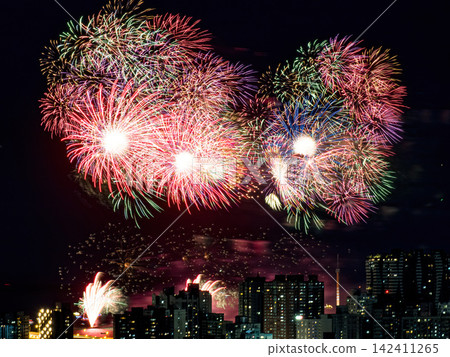 Spectacular colorful fireworks illuminating the night sky above a dense city skyline during a festive celebration. Spectacular colorful fireworks illuminating the night sky above a dense city skyline during a festive celebration. 142411265