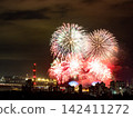 Spectacular colorful fireworks illuminating the night sky above a dense city skyline during a festive celebration. 142411272