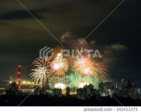 Spectacular colorful fireworks illuminating the night sky above a dense city skyline during a festive celebration. Spectacular colorful fireworks illuminating the night sky above a dense city skyline during a festive celebration. 142411273