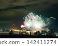 Spectacular colorful fireworks illuminating the night sky above a dense city skyline during a festive celebration. 142411274
