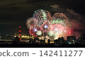 Spectacular colorful fireworks illuminating the night sky above a dense city skyline during a festive celebration. 142411277