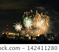 Spectacular colorful fireworks illuminating the night sky above a dense city skyline during a festive celebration. 142411280