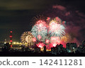 Spectacular colorful fireworks illuminating the night sky above a dense city skyline during a festive celebration. 142411281