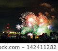 Spectacular colorful fireworks illuminating the night sky above a dense city skyline during a festive celebration. 142411282