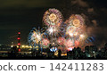 Spectacular colorful fireworks illuminating the night sky above a dense city skyline during a festive celebration. 142411283