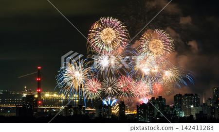 Spectacular colorful fireworks illuminating the night sky above a dense city skyline during a festive celebration. 142411283