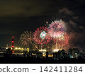 Spectacular colorful fireworks illuminating the night sky above a dense city skyline during a festive celebration. 142411284