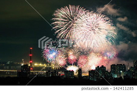 Spectacular colorful fireworks illuminating the night sky above a dense city skyline during a festive celebration. Spectacular colorful fireworks illuminating the night sky above a dense city skyline during a festive celebration. 142411285