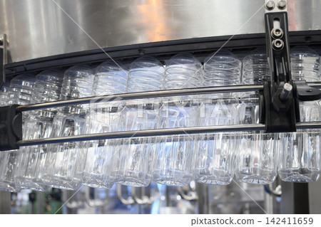 Overhead conveyor belt handling plastic bottles to filling process in drinking water factory Overhead conveyor belt handling plastic bottles to filling process in drinking water factory 142411659