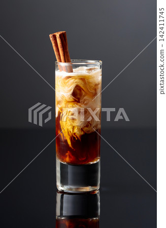 Cream and coffee liquor with ice in tall glass on a black background. Cream and coffee liquor with ice in tall glass on a black background. 142411745