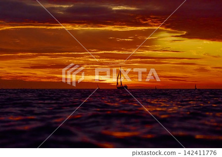 Yachtsmen are sitting amicably on board the boat at incredible sunset, sailing boat is in sailing regatta in the Gulf of Finland, magic splashing water, teamwork, Russia, St.Petersburg Yachtsmen are sitting amicably on board the boat at incredible sunset, sailing boat is in sailing regatta in the Gulf of Finland, magic splashing water, teamwork, Russia, St.Petersburg 142411776