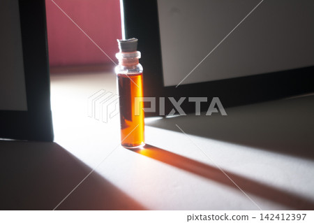 Vertical glass bottle filled with red liquid casting a long light beam on floor Vertical glass bottle filled with red liquid casting a long light beam on floor 142412397