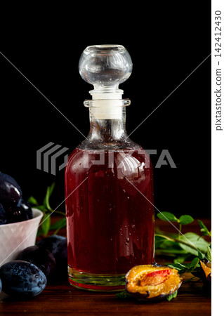 Traditional plum syrup with fresh plums on deep black background Traditional plum syrup with fresh plums on deep black background 142412430