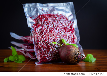 Fresh grated beet in sealed bags for freezing on wooden table 142412455
