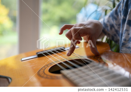Closeup of child hand playing acoustic guitar Closeup of child hand playing acoustic guitar 142412531