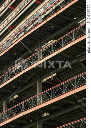 The structural beauty of a multi-story parking garage: the inorganic steel framework and railings are arranged in a regular pattern. The structural beauty of a multi-story parking garage: the inorganic steel framework and railings are arranged in a regular pattern. 142412611