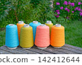 Large spools of colored industrial thread organized in rows 142412644