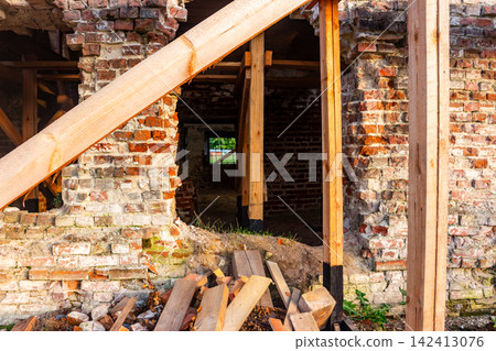 Heavy wooden scaffolding bracing and reinforcing the crumbling red brick walls of a derelict Orthodox church during structural stabilization and historic preservation works Heavy wooden scaffolding bracing and reinforcing the crumbling red brick walls of a derelict Orthodox church during structural stabilization and historic preservation works 142413076