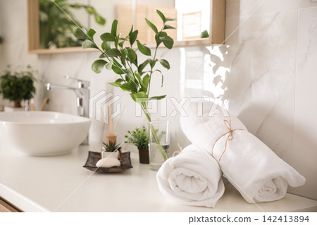 Towels and green plants on white countertop in bathroom. Interior design Towels and green plants on white countertop in bathroom. Interior design 142413894