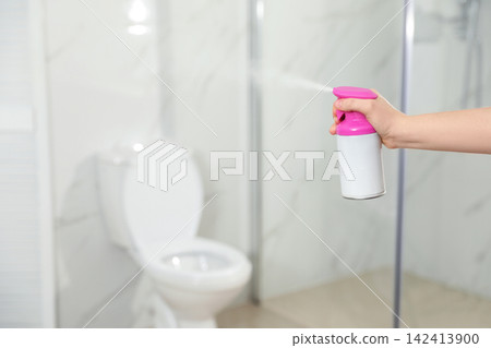 Woman spraying air freshener in bathroom, closeup Woman spraying air freshener in bathroom, closeup 142413900