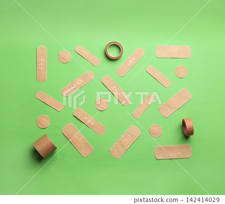 Different types of sticking plasters on green background, flat lay Different types of sticking plasters on green background, flat lay 142414029