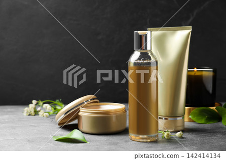 Cosmetic products and burning candle on grey stone table Cosmetic products and burning candle on grey stone table 142414134