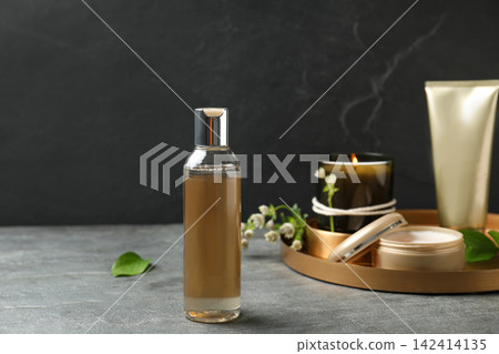 Cosmetic products and burning candle on grey stone table Cosmetic products and burning candle on grey stone table 142414135