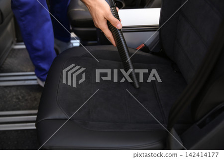Car wash worker vacuuming automobile seat, closeup Car wash worker vacuuming automobile seat, closeup 142414177