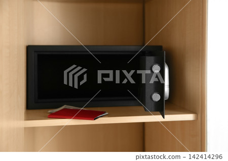 Open black steel safe in wooden closet 142414296