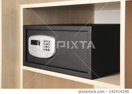 Black steel safe with electronic lock in wooden closet Black steel safe with electronic lock in wooden closet 142414298