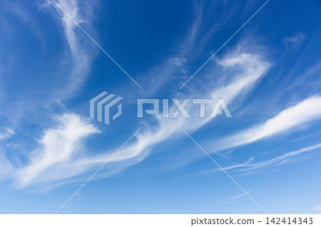 Wispy white cirrus clouds drift across a vibrant deep blue summer sky, creating graceful swirling patterns and ethereal formations in the vast atmospheric expanse during a clear day Wispy white cirrus clouds drift across a vibrant deep blue summer sky, creating graceful swirling patterns and ethereal formations in the vast atmospheric expanse during a clear day 142414343