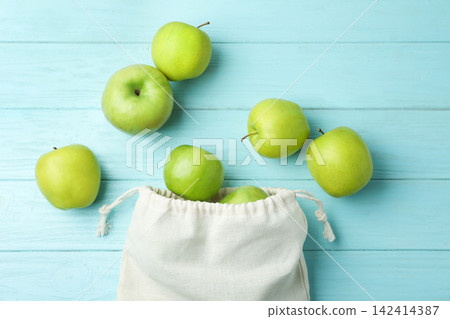 Cotton eco bag with apples on light blue wooden background, flat lay Cotton eco bag with apples on light blue wooden background, flat lay 142414387