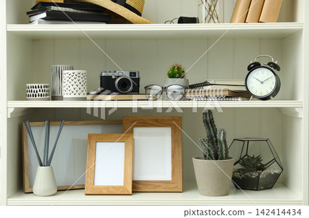 White shelving unit with photo frames and different decorative elements White shelving unit with photo frames and different decorative elements 142414434