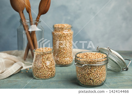 Uncooked green buckwheat grains on light blue wooden table Uncooked green buckwheat grains on light blue wooden table 142414466