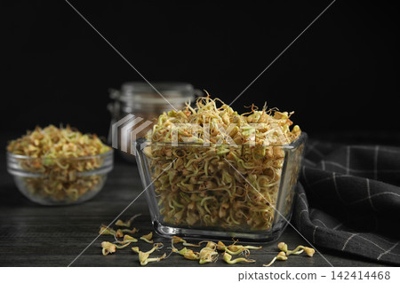 Glass bowl of sprouted green buckwheat on dark wooden table 142414468