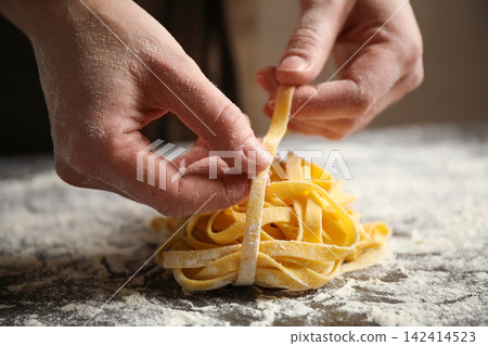 Woman holding pasta at table, closeup view Woman holding pasta at table, closeup view 142414523